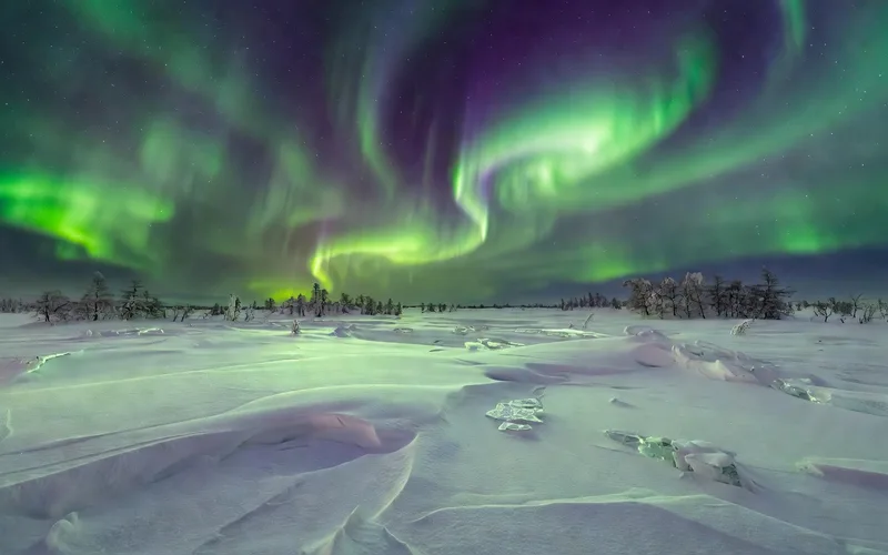 Aurores boreales vertes et violettes dansant au-dessus de la toundra enneigee du Grand Nord russe