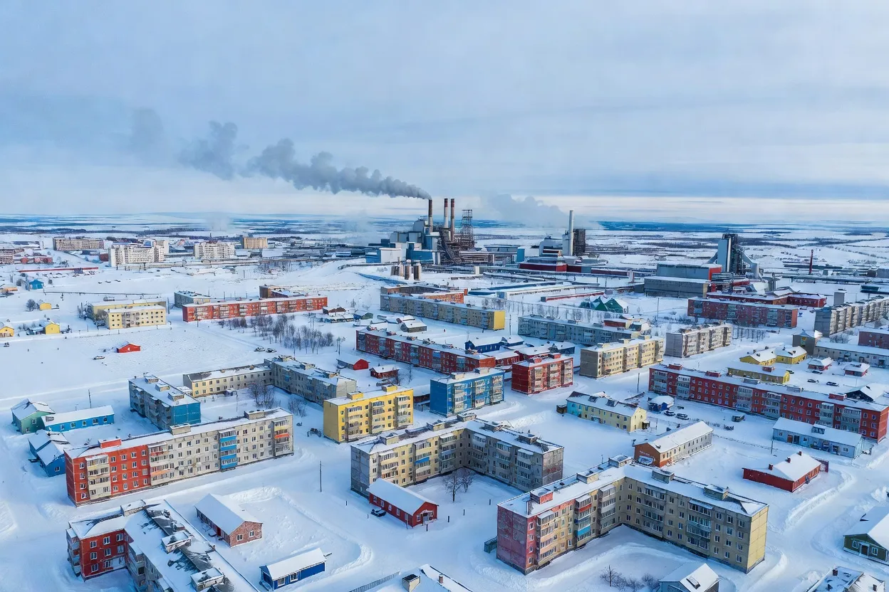 Vue de Norilsk en hiver, immeubles soviétiques colorés dans la neige avec les cheminées industrielles de Nornickel en arrière-plan